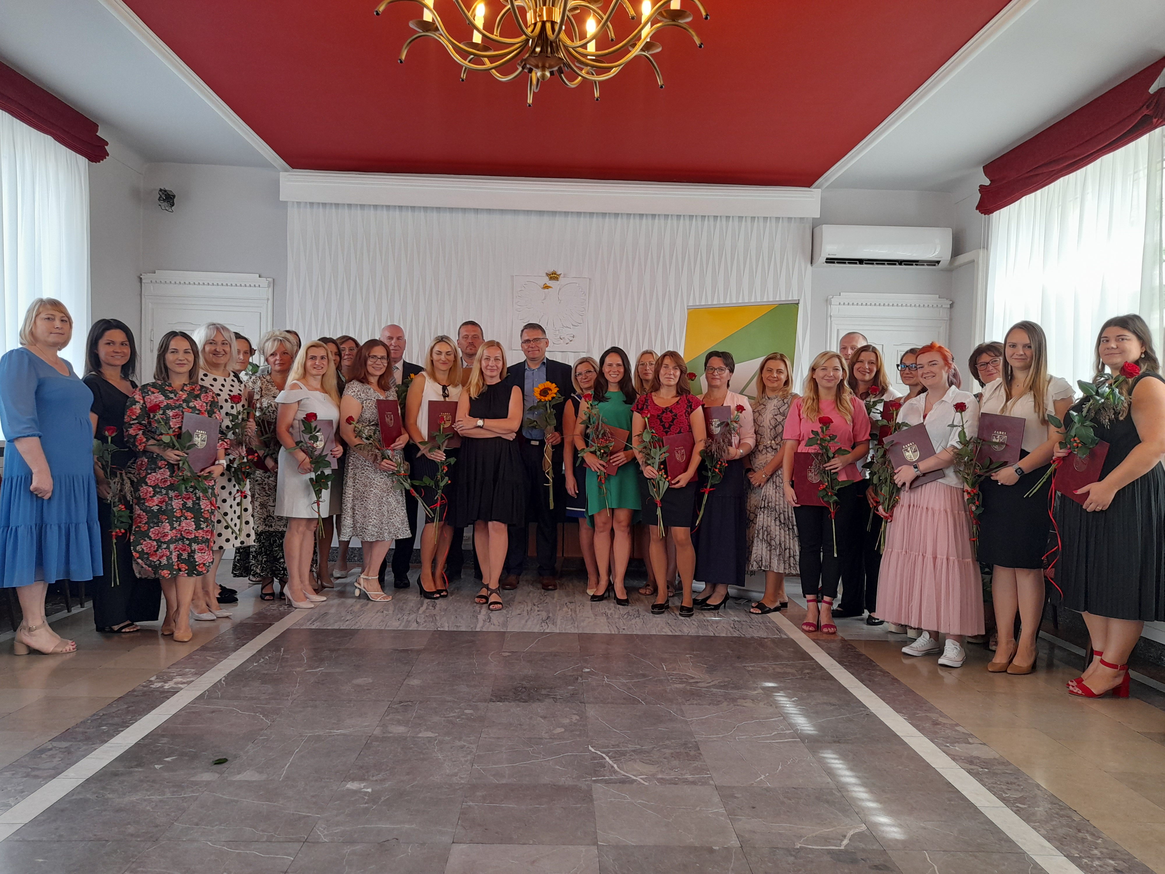 zdjęcie grupowe nauczycieli z aktami nadania i kwiatami